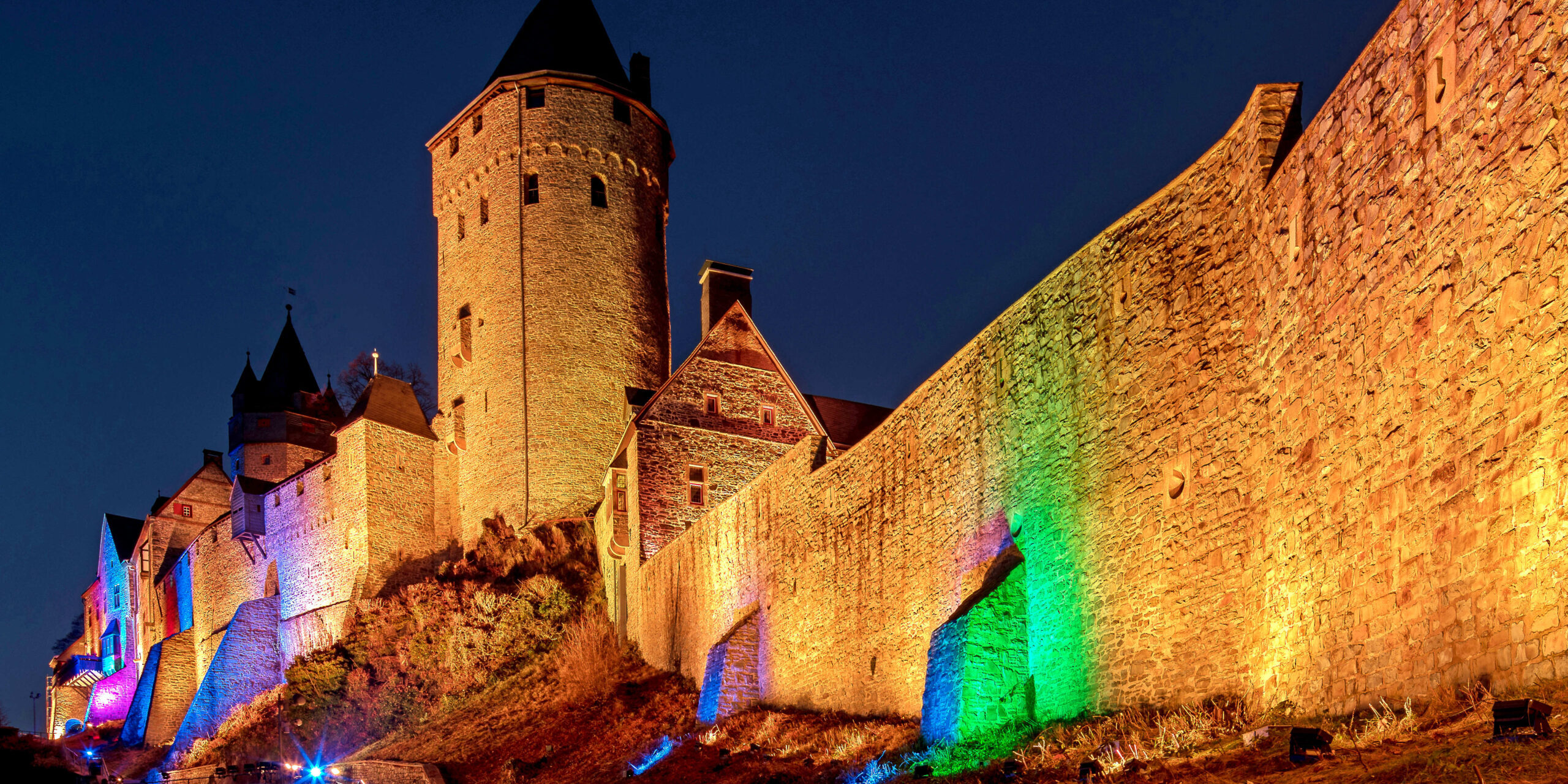 Die Burg Altena bei Nacht, beleuchtet in warmen Farben