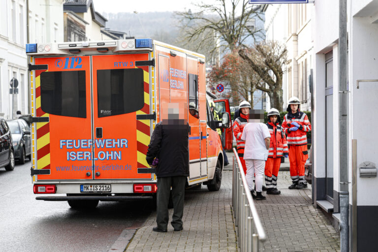 Rettungseinsatz mit Feuerwehr Iserlohn: Sanitäter und Passanten vor einem Einsatzfahrzeug in der Stadt.
