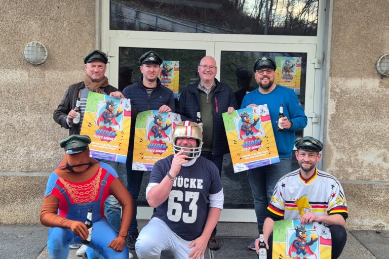 Sieben Männer vor einer Eingangstür, sie halten Werbeplakate in der Hand für die Motto-Party "Helden deiner Kindheit"