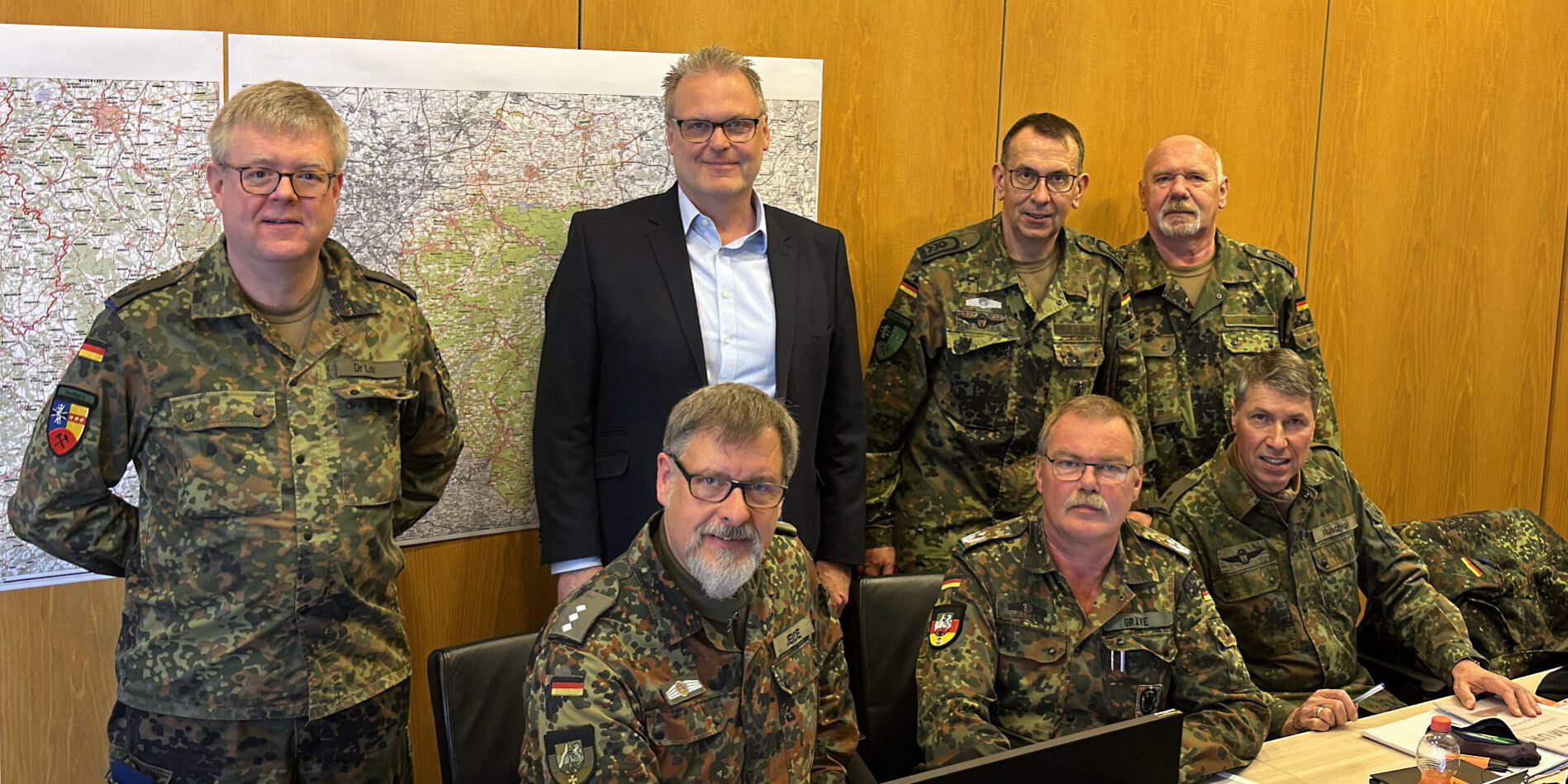 Im Kreishaus in Lüdenscheid fand jetzt eine groß angelegte Regionalübung mit Beteiligung der Bundeswehr statt.
© Foto: Märkischer Kreis Sechs Bundeswehrsoldaten und eine Person im Anzug stehen vor mehreren PC-Bildschrimen. Im Hintergrund eine Landkarte.