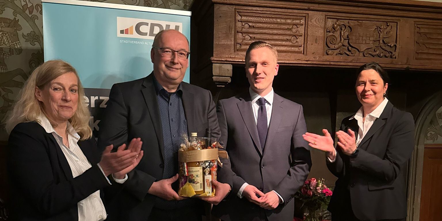 CDU-Politiker stehen in einem Raum vor einem Werbebanner.