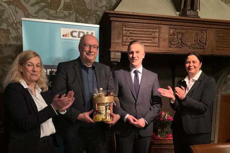 CDU-Politiker stehen in einem Raum vor einem Werbebanner.