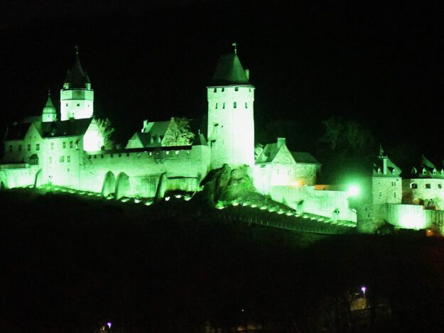 Die Burg Altena erstrahlt bei Nacht in grünem Licht.