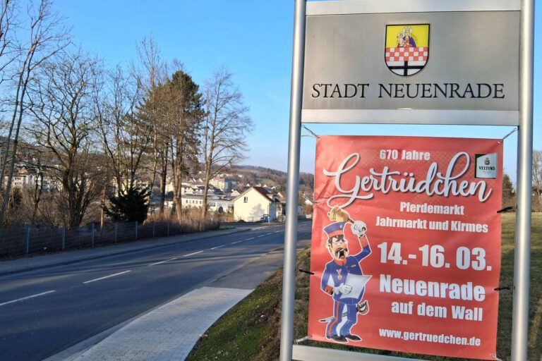 Ein Veranstaltungsplakat vom "Gertrüdchen" vor dem Ortsschild der Stadt Neuenrade.
