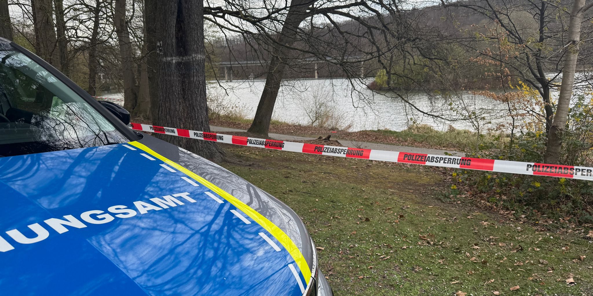 Ein Fahrzeug des Ordnungsamts steht vor einem Polizei-Flatterband. Im Hintergrund das Ufer vom Seilersee.