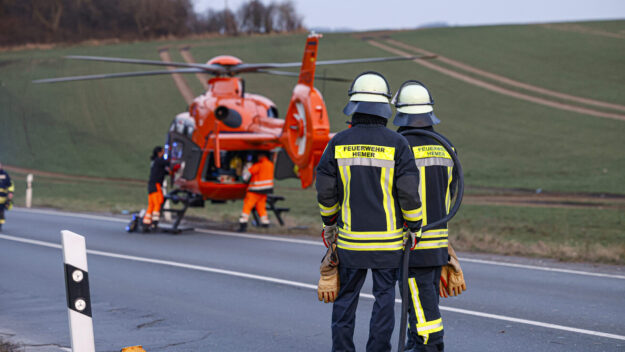 Foto: Dennis Echtermann Zwei Feuerwehrmänner stehen vor einem gelandeten Rettungshubschrauber.