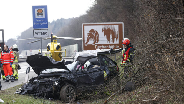 Foto: Dennis Echtermann Ein zerstörter schwarzer Pkw auf der Autobahn. Einsatzkräfte stehen drumherum, im Hintergrund ist ein Rettungshubschrauber gelandet.
