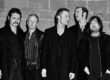 Eine Musikgruppe steht vor einer Wand. Das Bild ist schwarz-weiß.