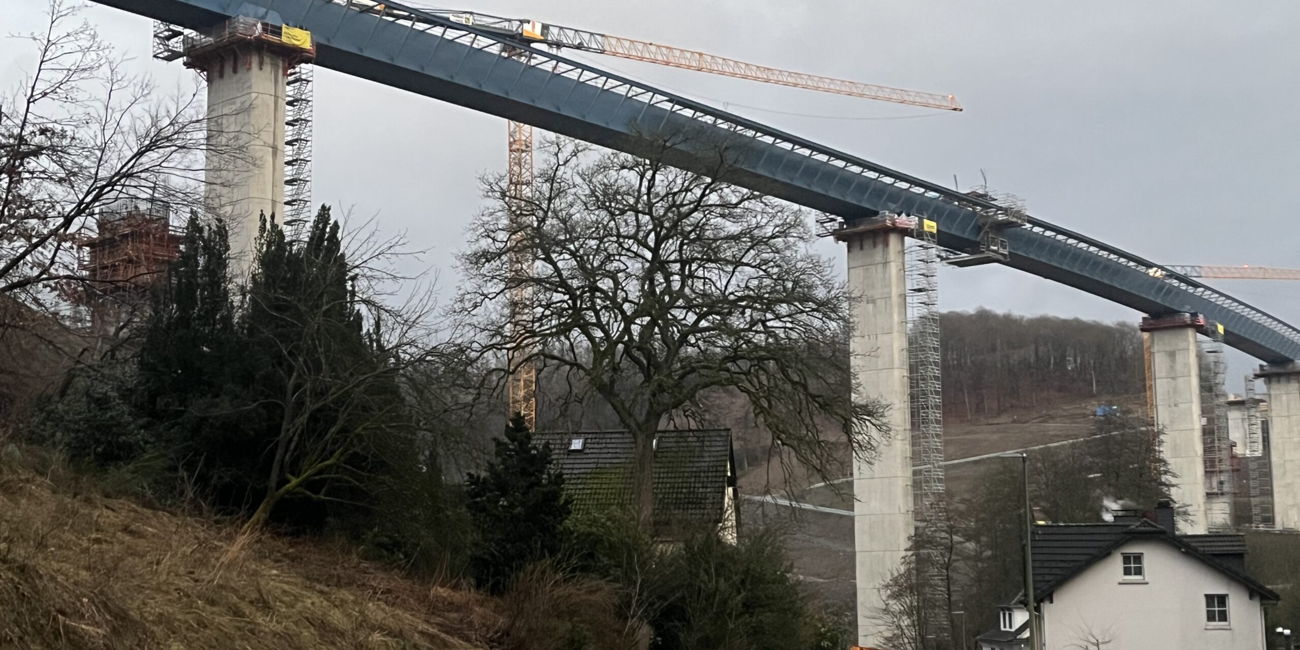 Eine Autobahnbrücke im Bau. Im Vordergrund steht ein Wohnhaus.