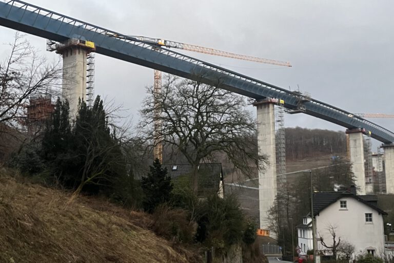 Eine Autobahnbrücke im Bau. Im Vordergrund steht ein Wohnhaus.