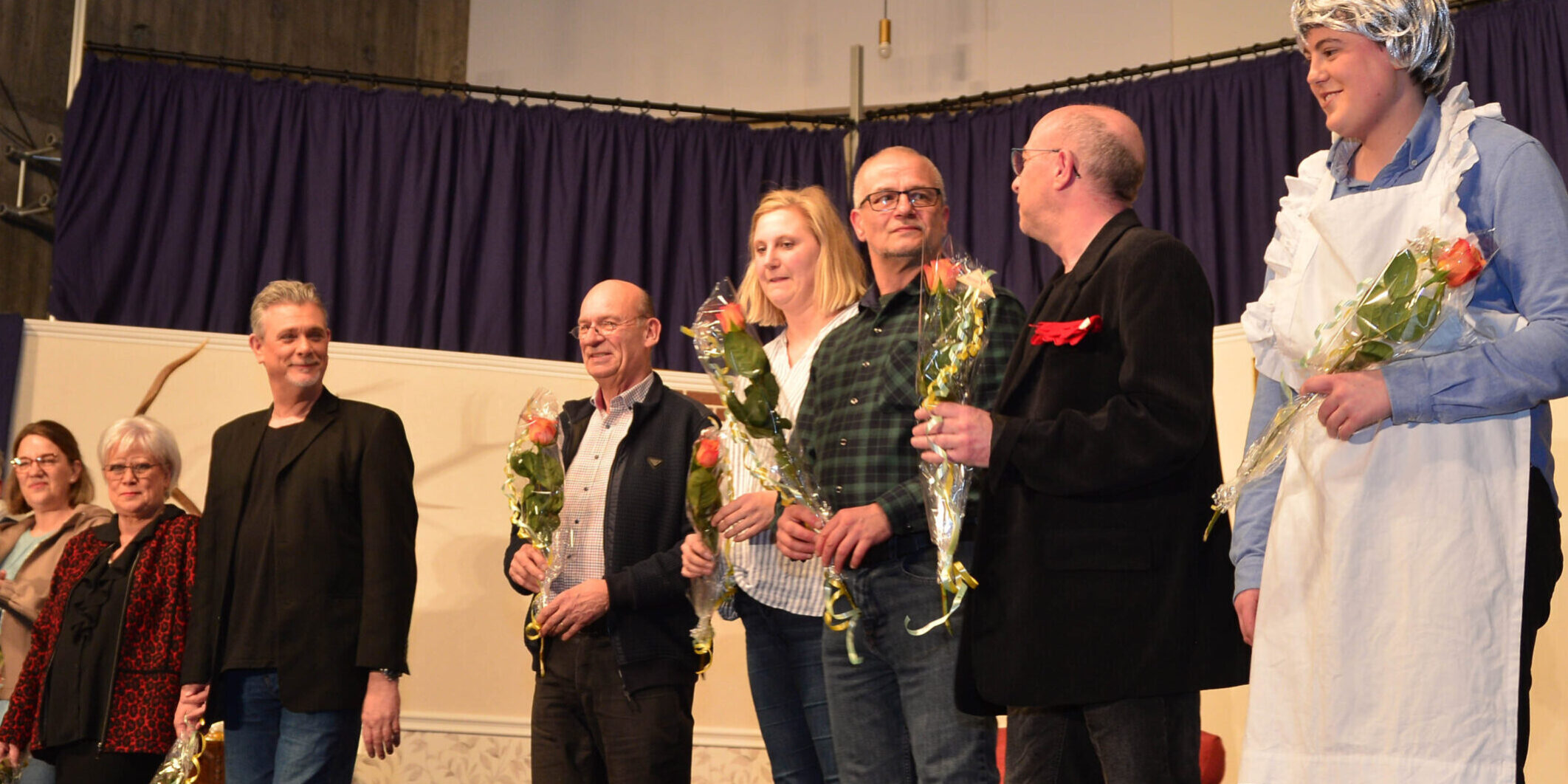 Schauspieler stehen auf der Bühne und halten Blumen in der Hand.