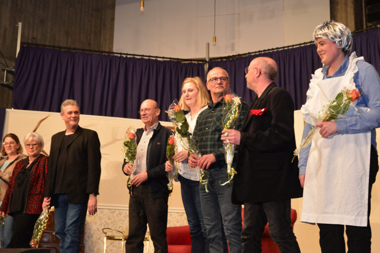Schauspieler stehen auf der Bühne und halten Blumen in der Hand.