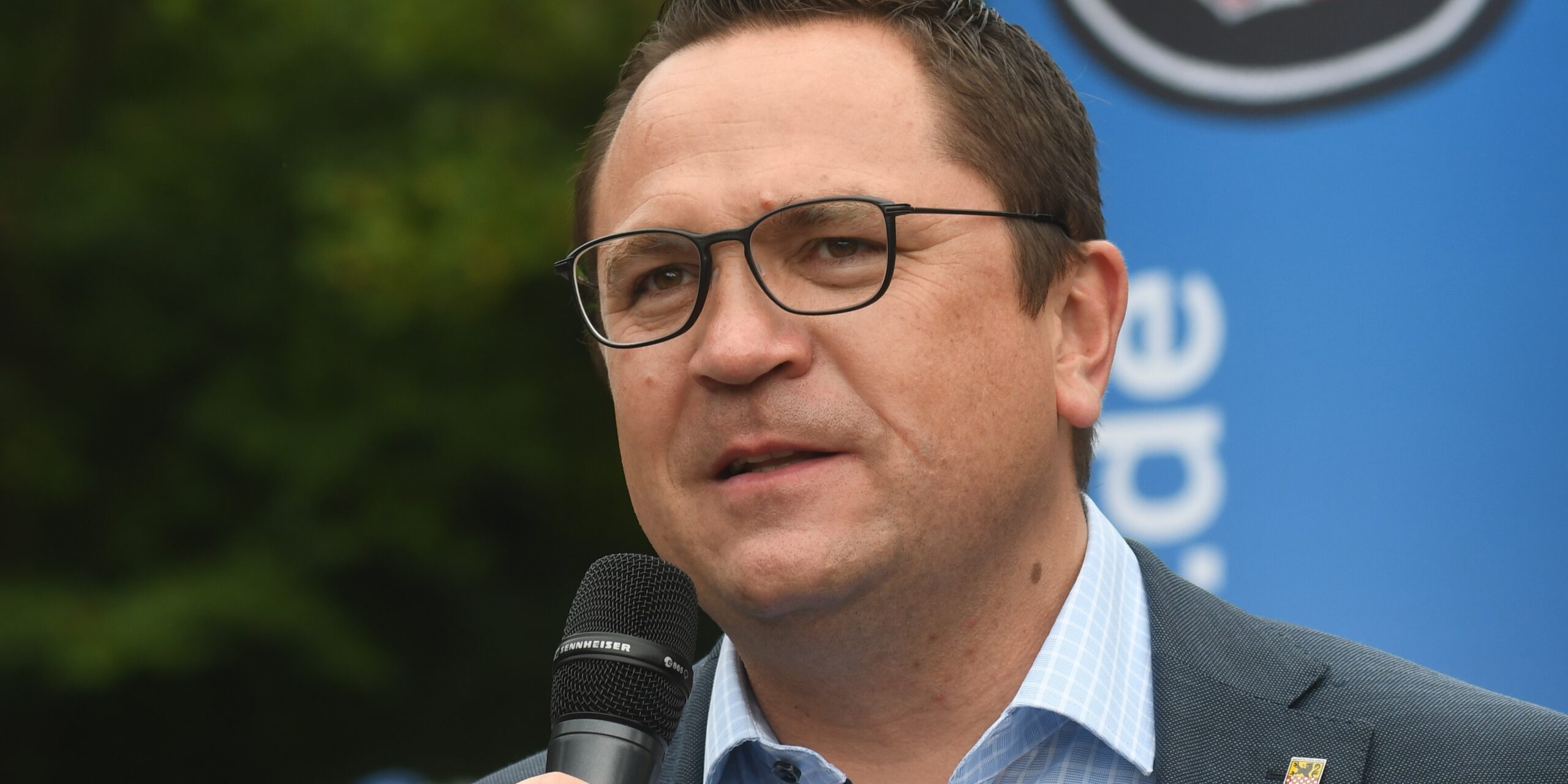 Landrat Marco Voge hält ein Mikrofon in der Hand.