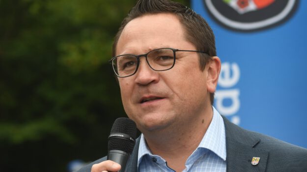Landrat Marco Voge hält ein Mikrofon in der Hand.