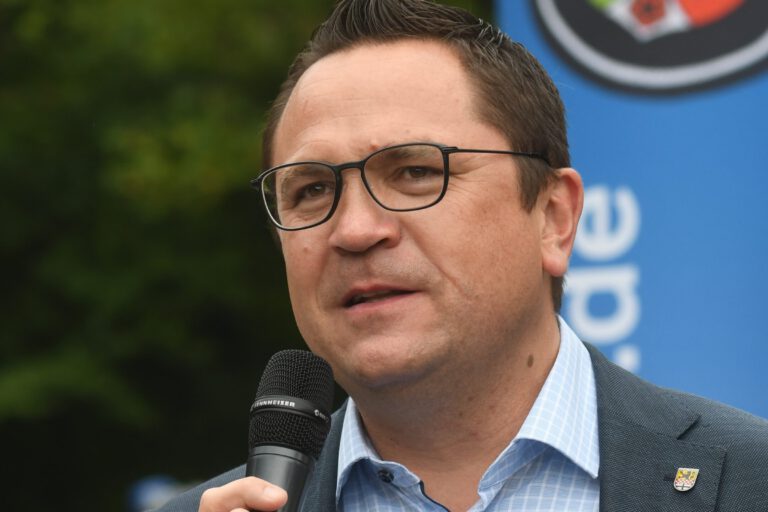Landrat Marco Voge hält ein Mikrofon in der Hand.