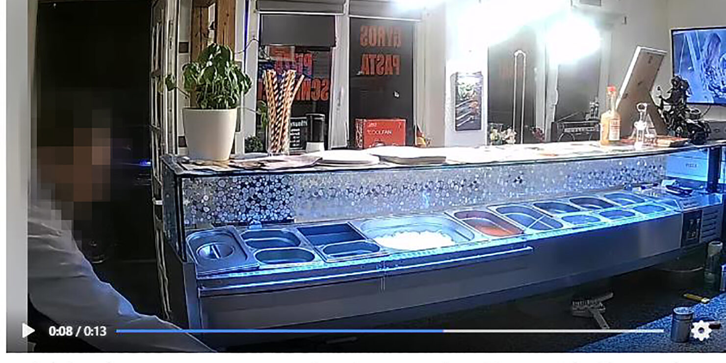 Facebook-Video einer Überwachungskamera, in dem ein Mann ein Handy hinter dem Verkaufstresen einer Pizzeria stiehlt.