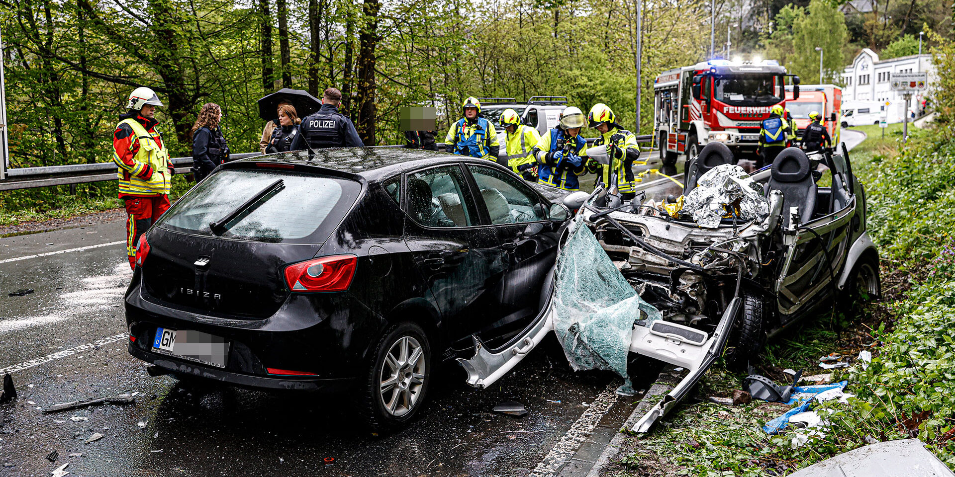 Schwerer Unfall auf der B 236 in Höhe Abzweig zum Knerling in Altena: Die Feuerwehr hat eine Person aus einem Pkw gerettet.
© Foto: Dennis Echtermann Zwei zerstörte Autos stehen nach einem Unfall auf der Straße. Im Hintergrund steht ein Feuerwehrfahrzeug und Rettungswagen. Einsatzkräfte von Polizei und Feuerwehr sind sichtbar.