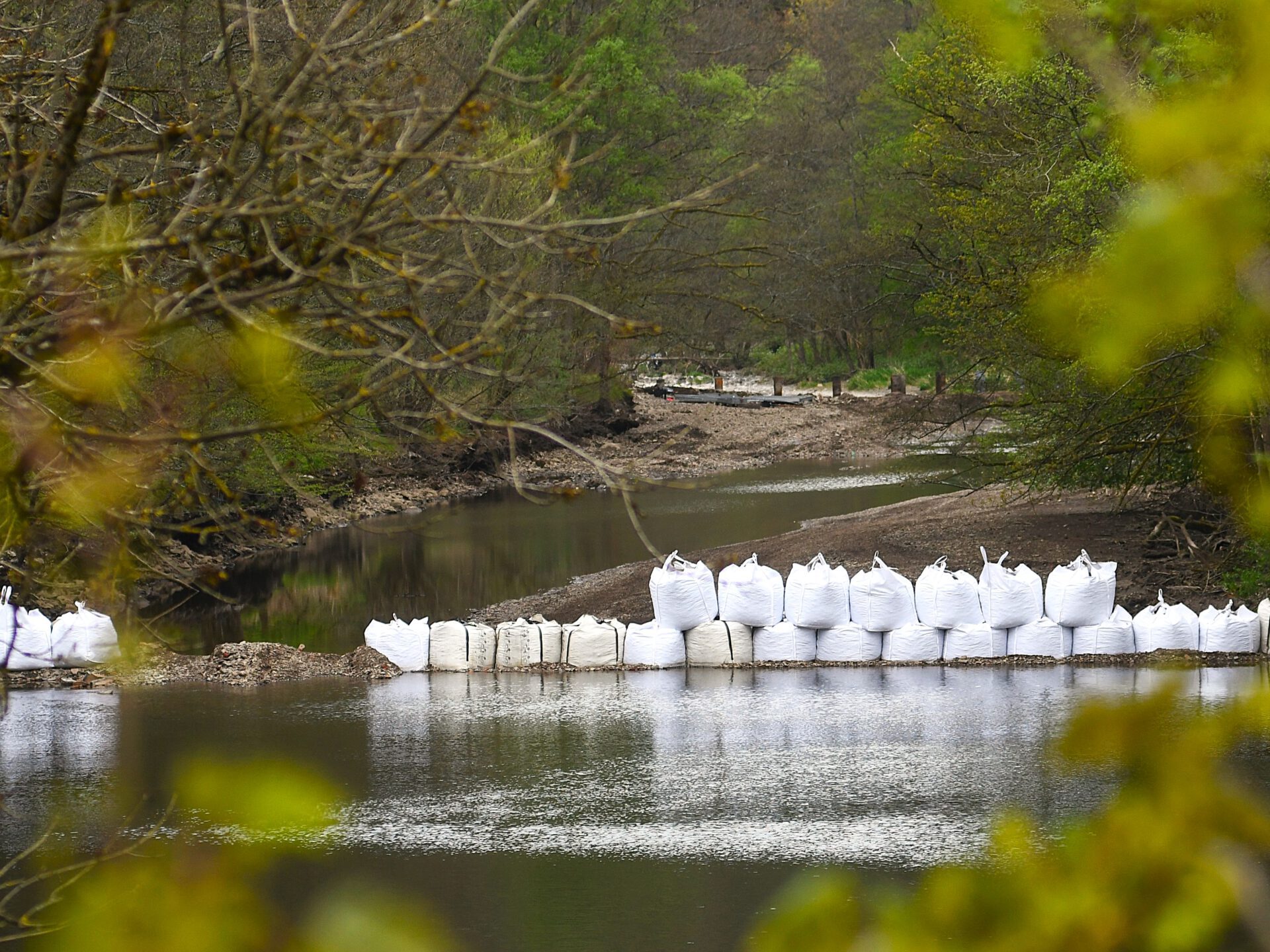 Große weiße Sandsäcke stehen in dem Fluss Lenne bei Altena.