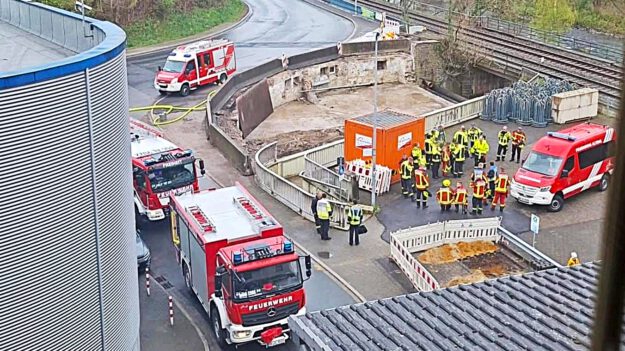 Foto: Feuerwehr Altena Mehrere Feuerwehrautos und Einsatzkräfte stehen vor einem Firmengebäude im Rahmen einer Übung.