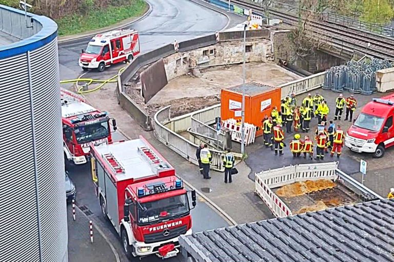 Mehrere Feuerwehrautos und Einsatzkräfte stehen vor einem Firmengebäude im Rahmen einer Übung.