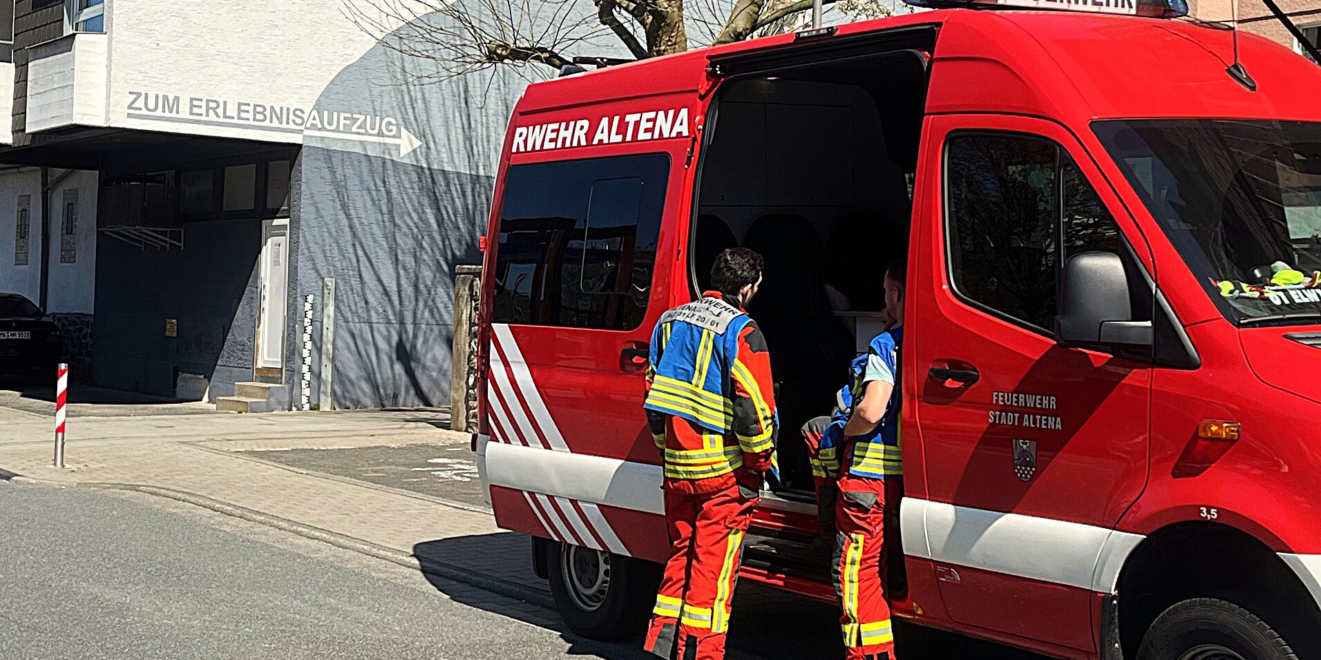Einsatzkräfte der Feuerwehr Altena stehen an einem Einsatzfahrzeug.