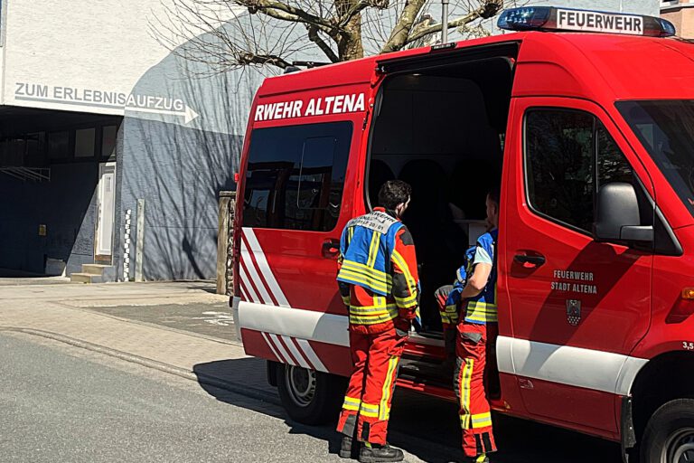 Einsatzkräfte der Feuerwehr Altena stehen an einem Einsatzfahrzeug.