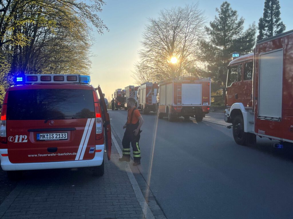 Das Bild zeigt mehrere Feuerwehrfahrzeuge im Gegenlicht der untergehenden Sonne.