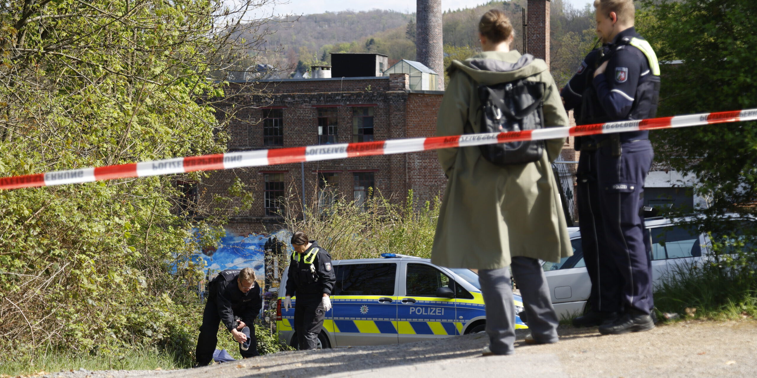 Nach dem Unfall am Pastorenweg in Iserlohn sicherte die Polizei eine Vielzahl von Spuren.
© Foto: Dennis Echtermann Ermittler von der Polizei stehen hinter einer Polizeiabsperrung und untersuchen Spuren auf dem Boden.