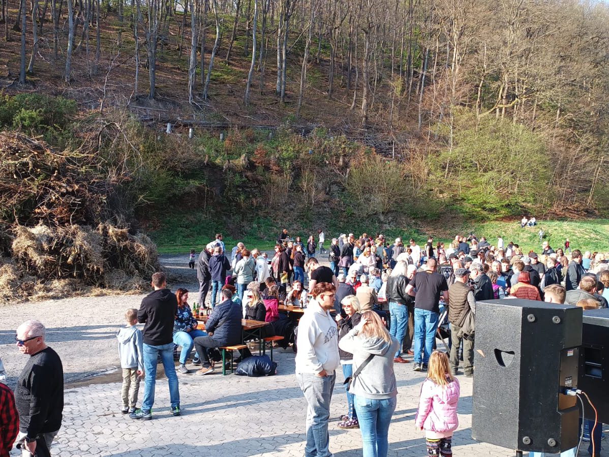Osterfeuer bei Tageslicht, umgeben von zahlreichen Besuchern.