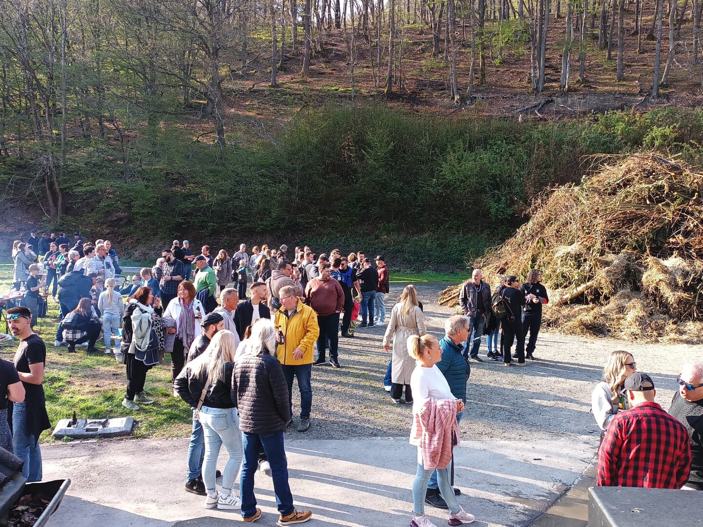 Osterfeuer bei Tageslicht, umgeben von zahlreichen Besuchern.