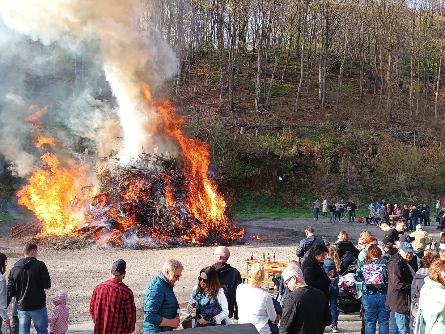 Osterfeuer bei Tageslicht, umgeben von zahlreichen Besuchern.