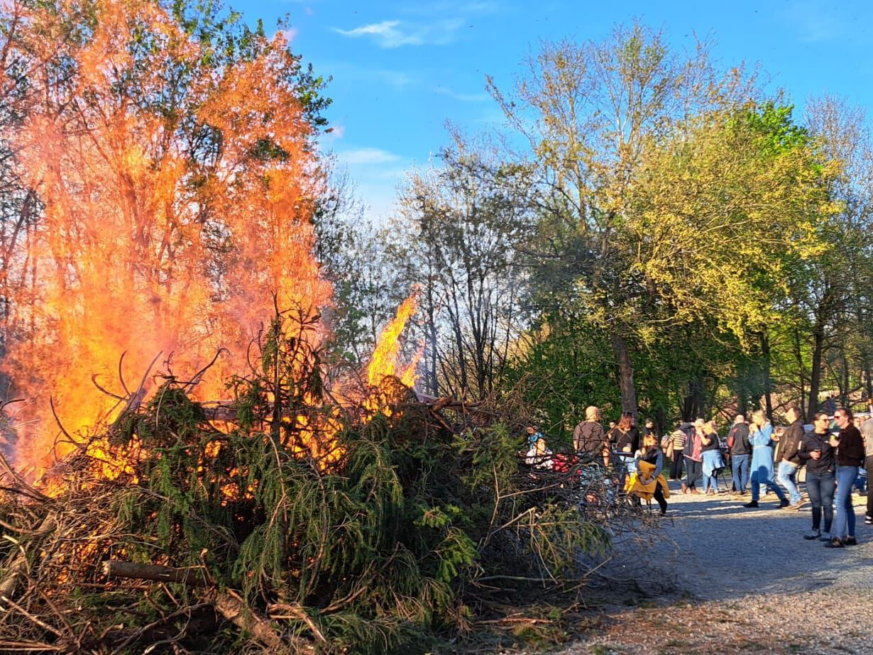 Osterfeuer bei Tageslicht, umgeben von zahlreichen Besuchern.
