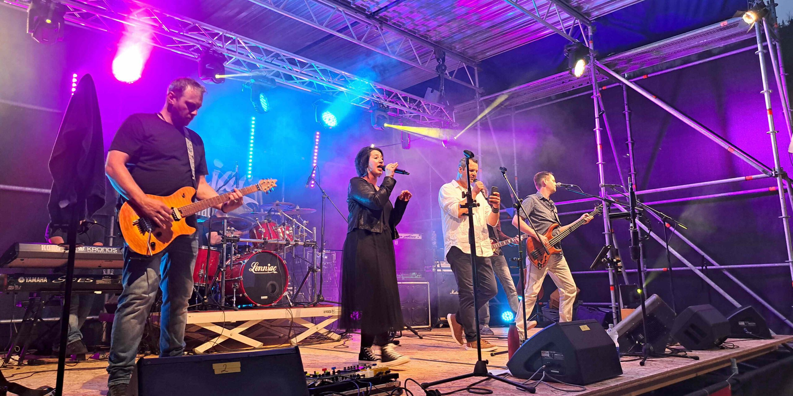 Eine Band performt im Scheinwerferlicht auf einer Bühne.