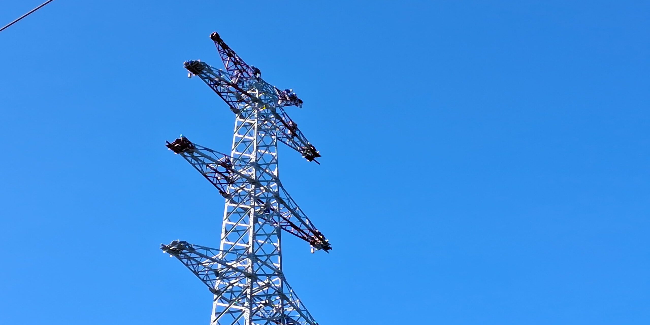 Samstagmorgen um kurz nach neun: 13 Mastenstreicher beginnen in schwindelerregender Höhe mit ihrer Arbeit.
© Foto: Ilka Kremer Ein Strommast vor blauem Himmel.
