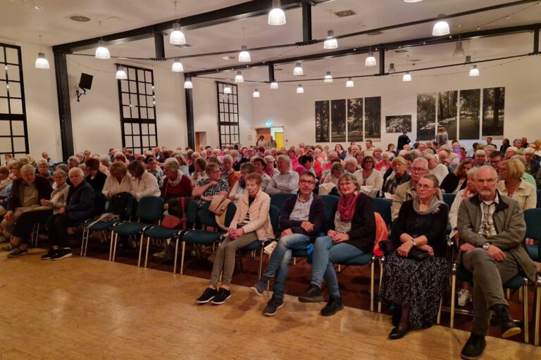 Foto: Freies Theater Auf Draht Altena Zuschauer sitzen in Stuhlreihen in einem beleuchteten Saal.
