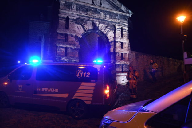Foto: Carsten Menzel Ein Polizei- und Feuerwehrfahrzeug stehen bei Nacht vor den Burgmauern der Burg Altena.