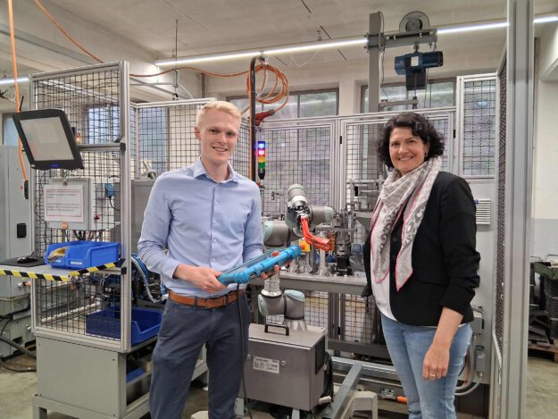 Foto: Ilka Kremer Zwei Personen stehen vor einem Roboter und halten ein Tablet in der Hand.