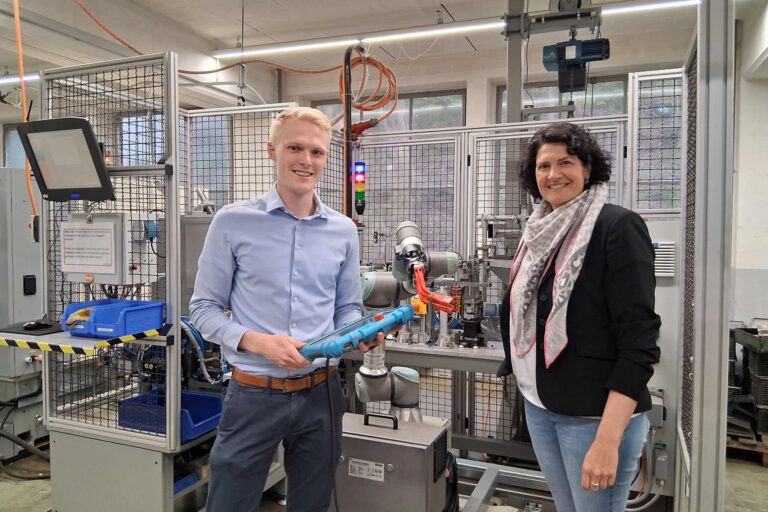 Foto: Ilka Kremer Zwei Personen stehen vor einem Roboter und halten ein Tablet in der Hand.
