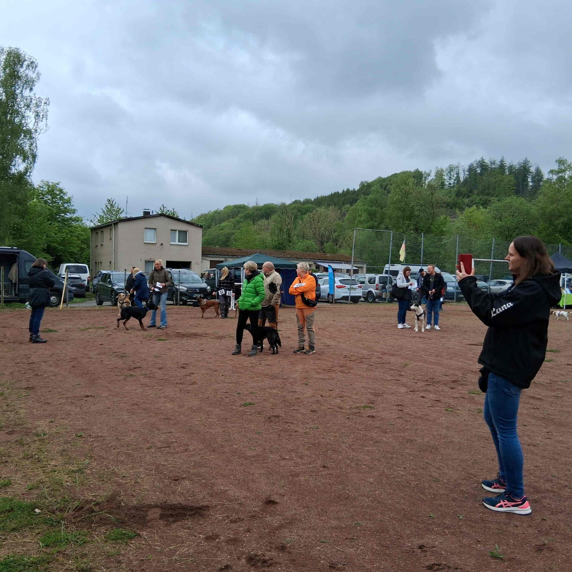 Ein Hund im vollen Lauf auf einer Wiese während eines Hunderennens, Zuschauer im Hintergrund.