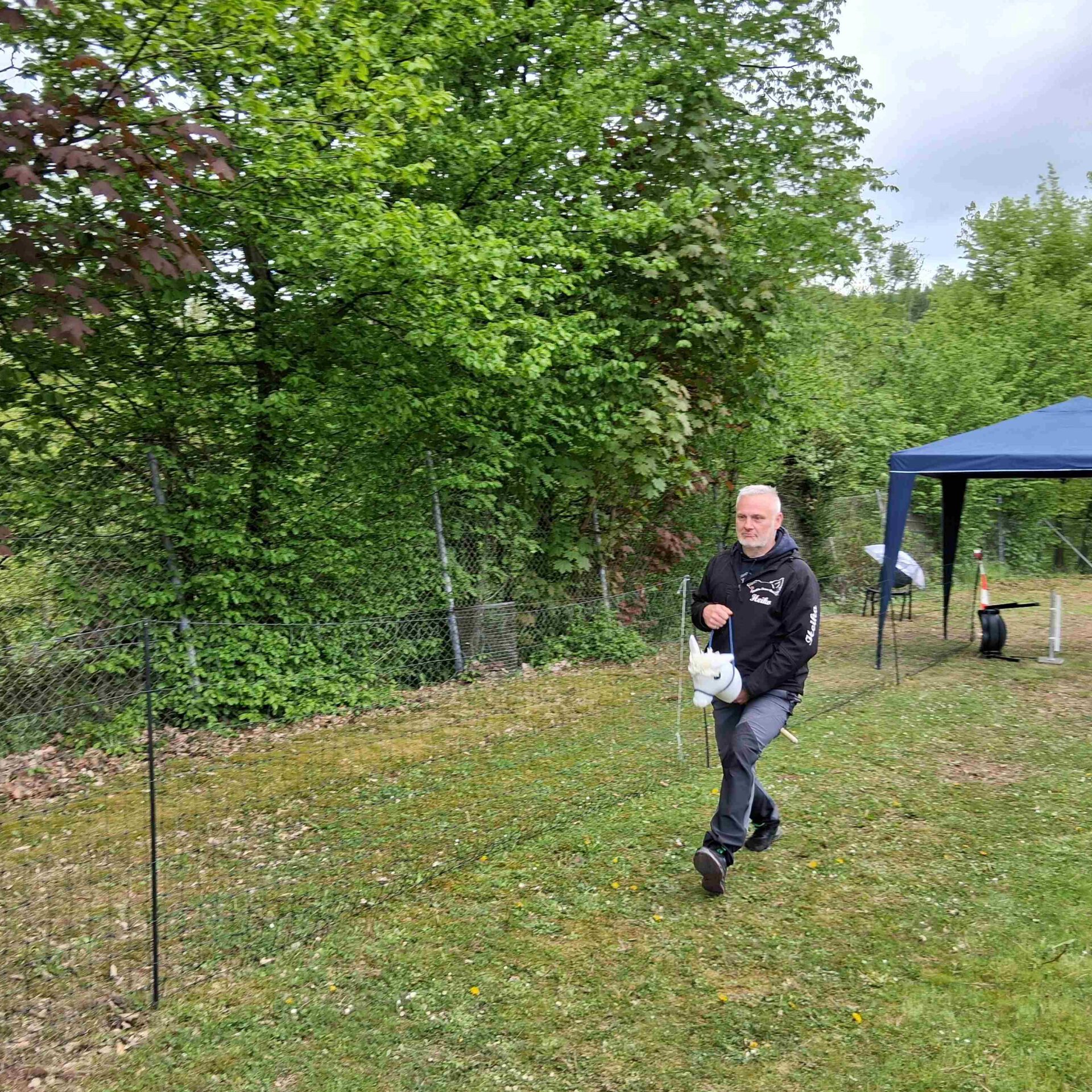 Ein Mann rennt beim Hunderennen auf einem Holzpferd über die Strecke.