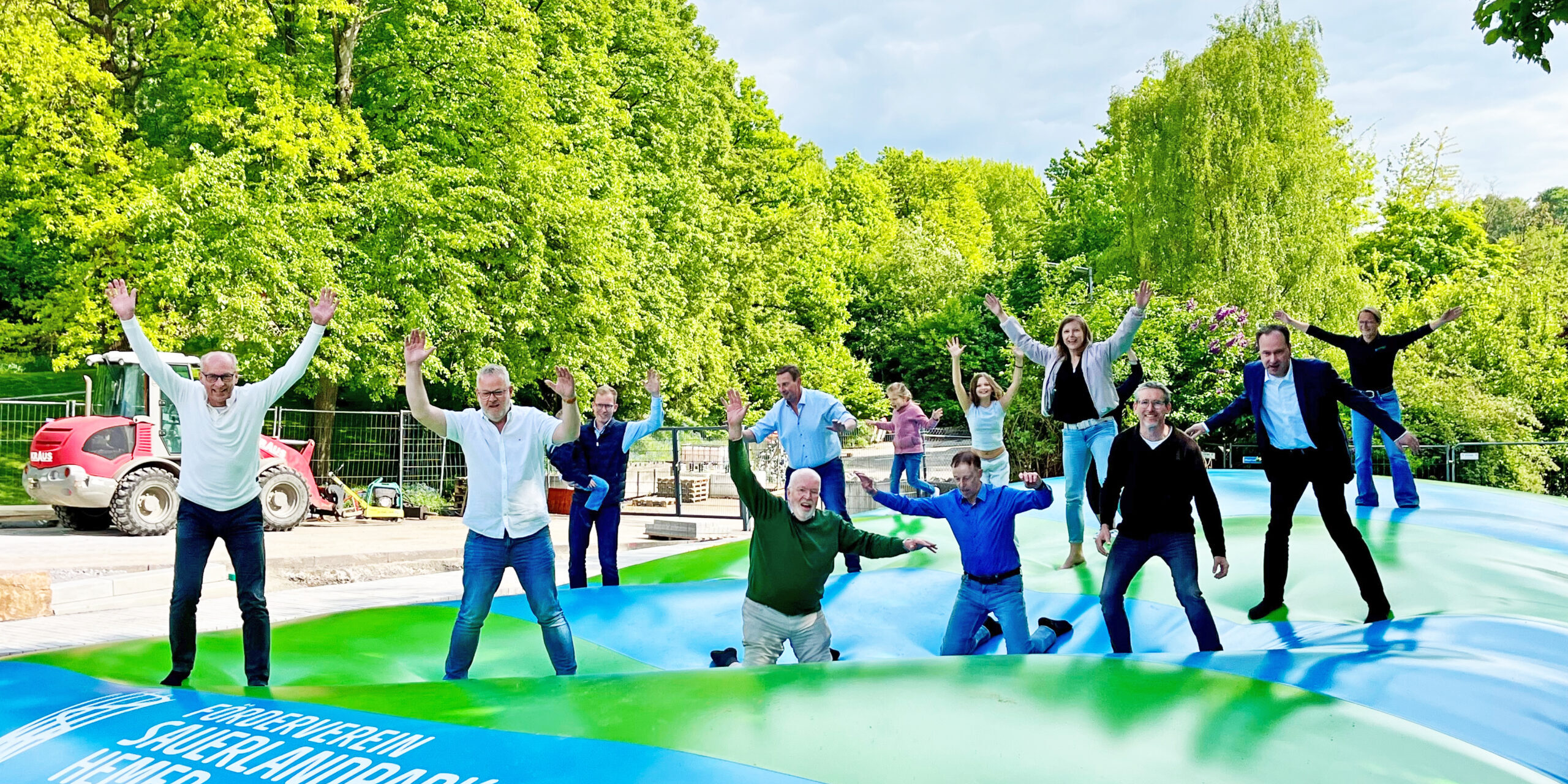 Erwachsene hüpfen auf einem großen Hüpfkissen.