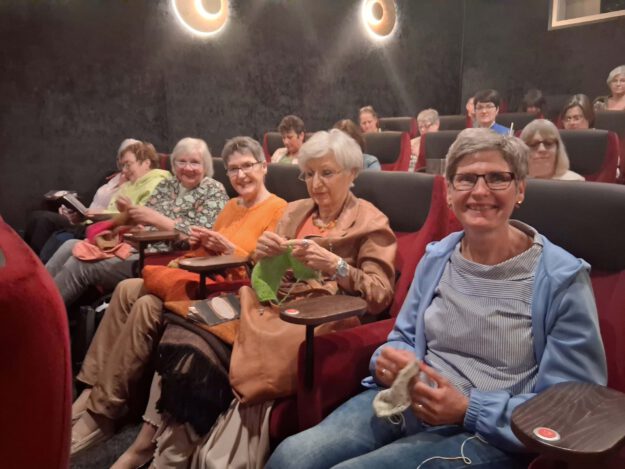 Foto: Ilka Kremer Mehrere Frauen sitzen in einem dunklen Kinosaal und stricken während einer Filmvorstellung.