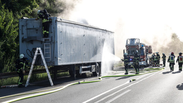 Die Feuerwehr löscht einen brennenden Lkw-Auflieger auf der Autobahn.