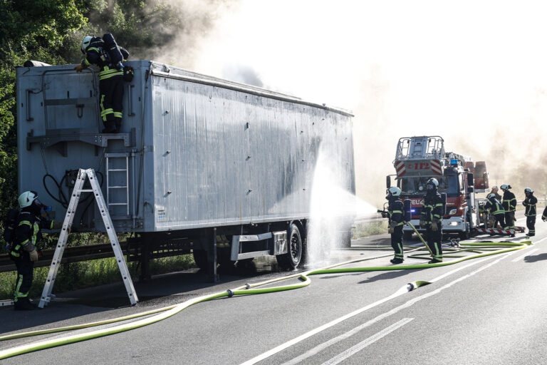Die Feuerwehr löscht einen brennenden Lkw-Auflieger auf der Autobahn.
