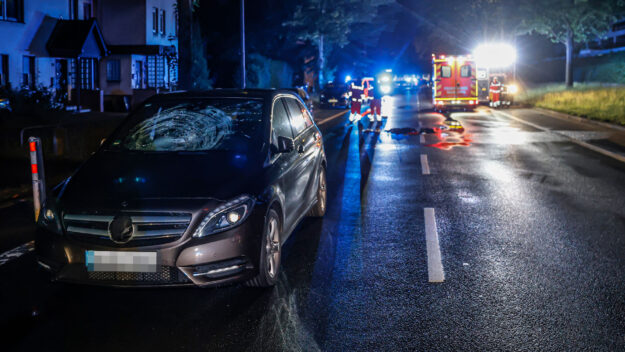 Foto: Dennis Echtermann Ein Unfallwagen steht mit beschädigter Windschutzscheibe in der Nacht auf einer Straße. Rettungskräfte arbeiten im Hintergrund.