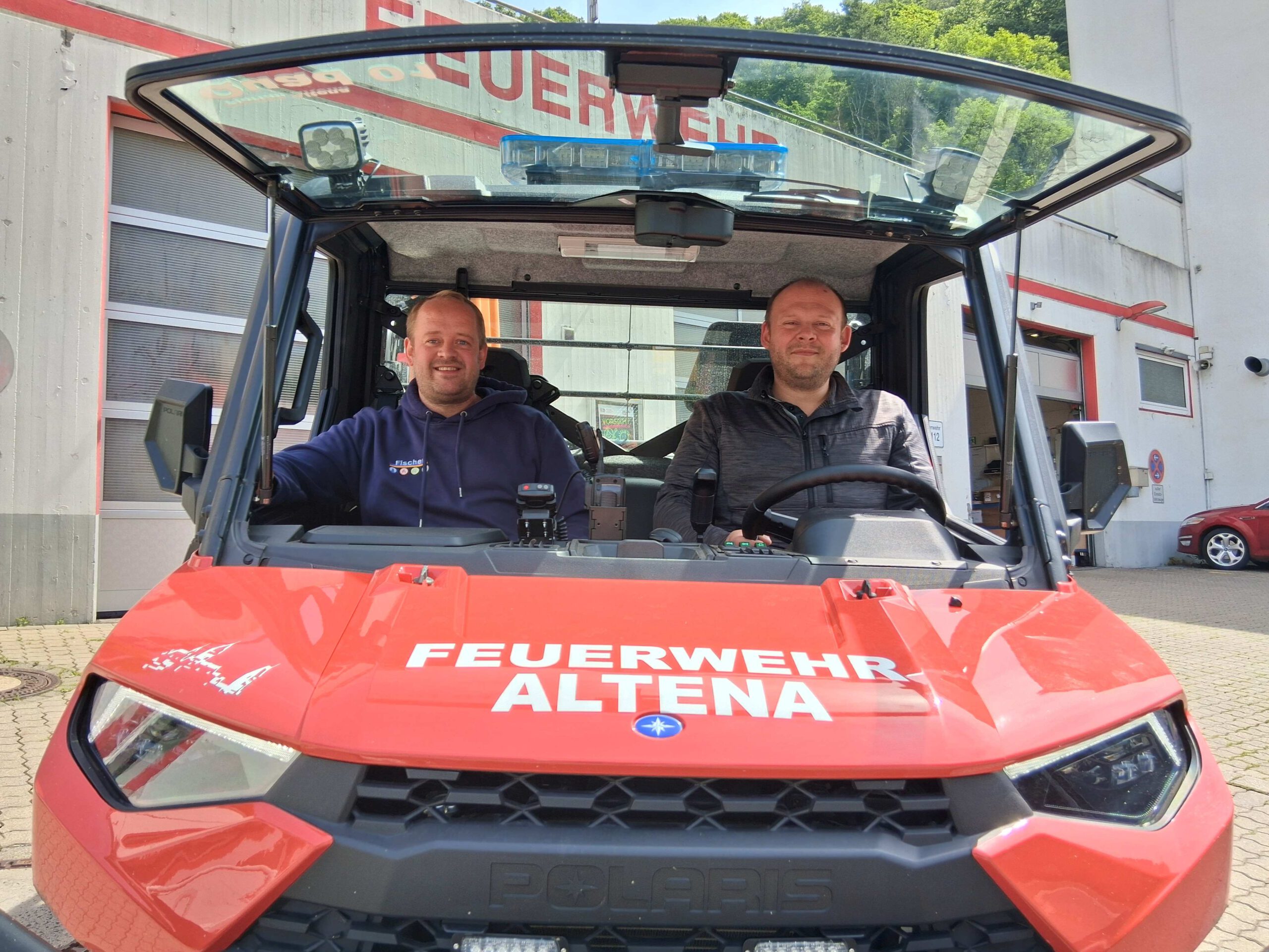 Zwei Männer sitzen in einem kleinen Geländewagen.