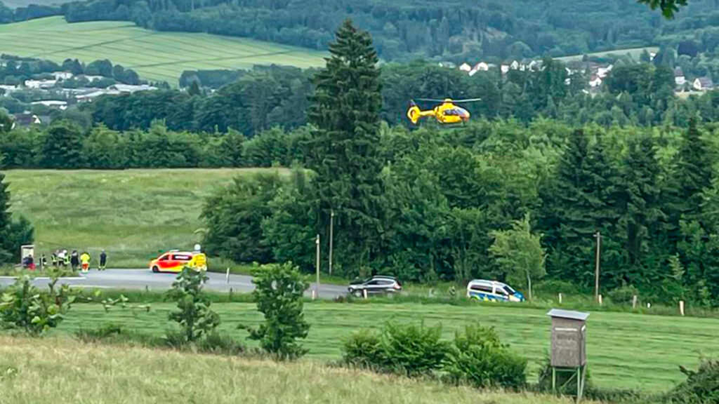 Ein ADAC Rettungshubschrauber startet auf einer Wiese.