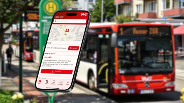 Ein Smartphone, auf dem die neue MVG-App aufgerufen ist vor einem Hintergrund-Foto, das verschwommen einen Bus der MVG an einer Haltestelle zeigt.