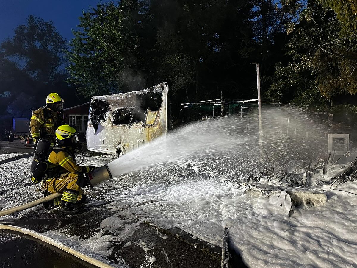 Einsatzkräfte der Feuerwehr ersticken das Feuer mit Schaum.