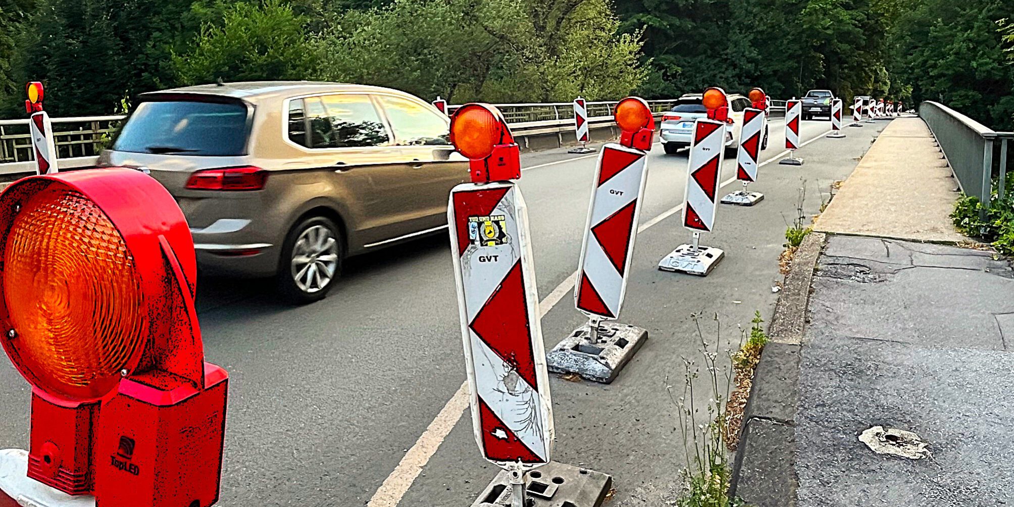 Die Fahrbahn auf einer Brücke ist mit rot-weißen Baken auf eine Fahrspur in der Mitte verengt, über die Autos in Richtung Norden fahren